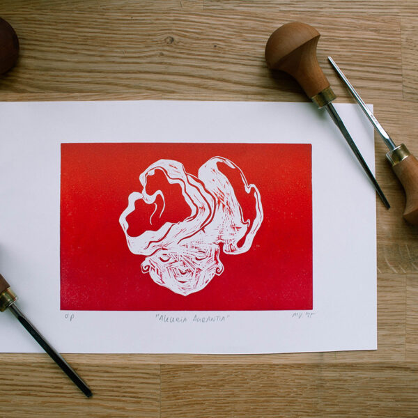 linoleumprent in gradiënt oranje-rood van paddenstoelenhoofdje op papier. met linogutsen