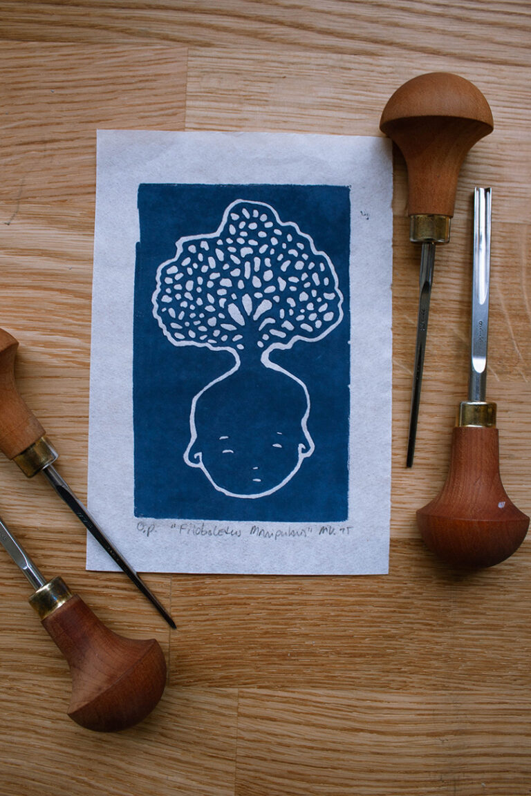 linoleumprent in donkerblauw van paddenstoelenhoofdje op papier. met linogutsen