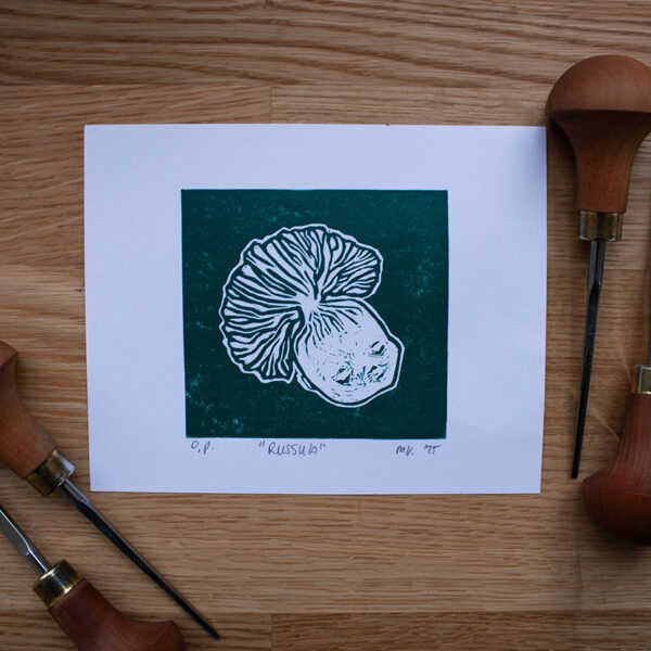 linoleumprent in donkergroen van paddenstoelenhoofdje, op papier. met linogutsen