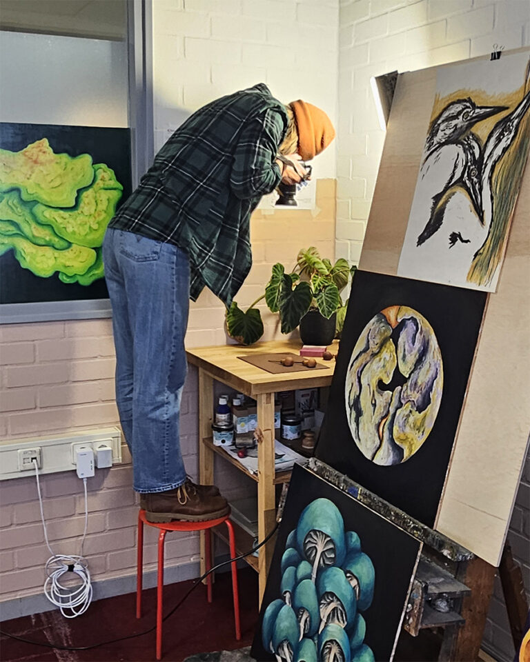 kunstenaar fotografeert van bovenaf. omringt door schilderijen en tekeningen